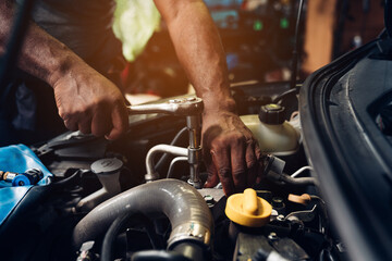 Closeup of auto mechanic are using the wrench to repair and maintenance auto engine is problems at car repair shop.