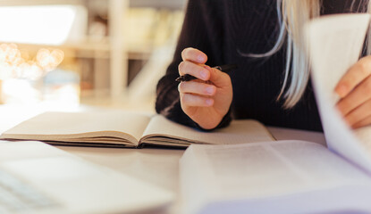 Close-up of female reading books on desk in library