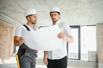 Male Architect Giving Instructions To His Foreman At Construction Site.