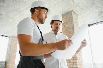 Construction concept of Engineer and Architect working at Construction Site with blue print.