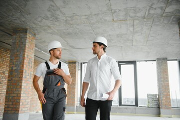 Male Architect Giving Instructions To His Foreman At Construction Site.