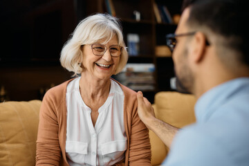 Happy senior woman talks to male caregiver during home visit.