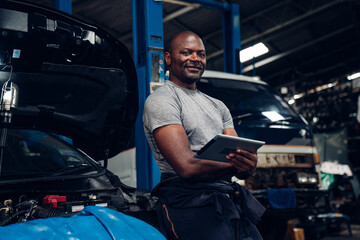 Fototapeta na wymiar Portrait of an auto mechanic holding tablet at the repair garage. Repair service.