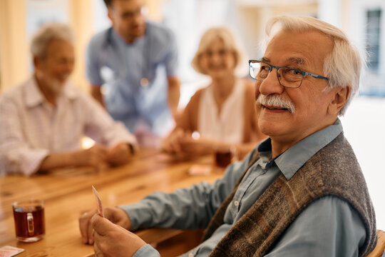 Happy senior man playing poker with his friends at retirement community.