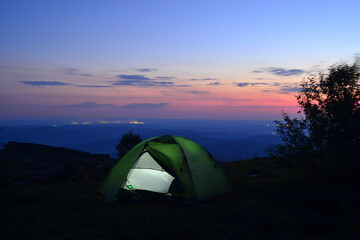 Tent on top of the mountain. Night landscape. Sunset. Bird's eye view, city and mountains.