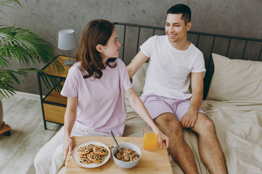 Top View From Above Young Couple Two Family Man Woman She He Wear T-shirt Pajama Eat Breakfast Sit In Bed Rest Spend Time Together On Weekends In Bedroom Home In Own Room Hotel. Real Estate Concept.