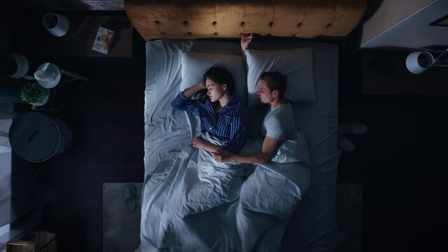 Top View Apartment: Happy Young Couple Side Cuddling Together in the Bed Sleeping at Night. Beautiful Girlfriend and Handsome Boyfriend Sleeping Together. Family of two Sweetly Embracing, Spooning