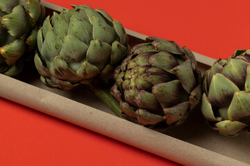 Fototapeta premium Big fresh green artichokes on a red background.