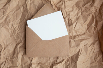 Blank card with kraft brown paper envelope template mock up on crumpled brown paper