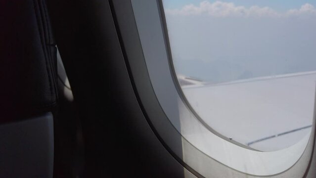 View from in side plane cabin through plane window while flying above sky