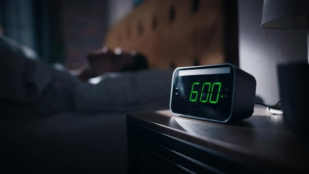 Man Wakes Up and Turns off Alarm Clock. Early Rising Productive Man Ready Start a Day of Business Projects. Focus on the Clock Showing Six O'Clock. Cinematic Slow Motion. Nightstand bedroom Apartment