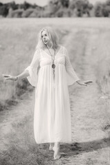 Ethnic hippie woman posing in boho long white lace dress at nature. Concept of ethnos style