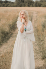 Ethnic hippie woman posing in boho long white lace dress at nature. Concept of ethnos style