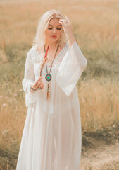 Fototapeta na wymiar Ethnic hippie woman posing in boho long white lace dress at nature. Concept of ethnos style