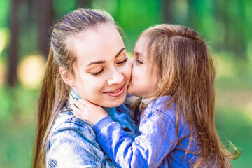 Daughter in the arms of my mother, kisses, hugs. Tenderness, love. On the background of trees, close-up