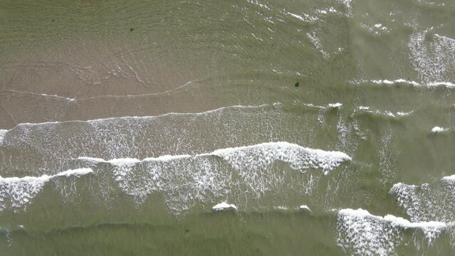 Foamy waves of the north pacific ocean crashing ashore at British Columbia's sunshine coast. Static aerial top down view