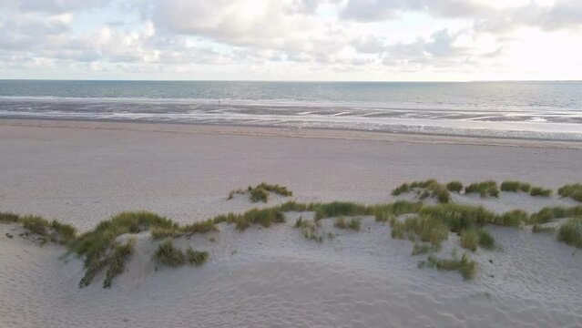 Sliding aerial footage of dunes at the north sea shore in the Netherlands during golden hour