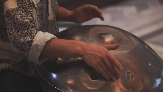 SLOW MOTION: Close-up of a a street performer playing handmade percussion made of metal frying pan on footpath.