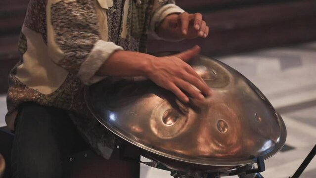 SLOW MOTION: A street performer playing handmade percussion made of metal frying pan on footpath.