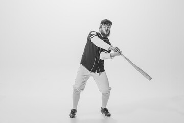 Monochrome portrait of male baseball player wearing retro sports uniform and holding bat isolated on white background. Vintage baseball batter