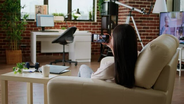 Asian woman discussing with executive manager on phone online video call while doing remote work from home. Young adult person talking with coworker on phone video call while working remotely.