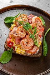 Big nutritious healthy sandwich with shrimp, egg, tomatoes and greens in a  plate on a marble background. Restaurant banquet menu.