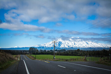 A mountain highway leading towards snow capped peaks of Mt Ruapehu and Mt Ngauruhoe. Tongariro National Park, New Zealand
