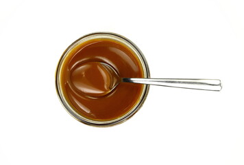 Sweet caramel sauce in a transparent bowl isolated on white background close up. Golden Butterscotch toffee caramel liquid. Melted caramel sauce drop.