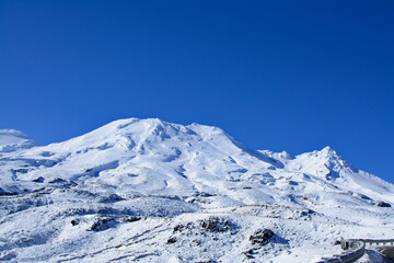 Fototapeta na wymiar Majestic peaks of Mountain Ruapehu covered with beautiful winter snow. Tongariro National Park, North Island of New Zealand on a bright sunny day