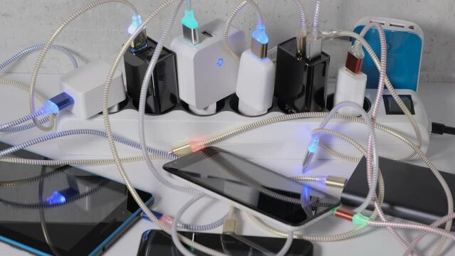 Mobile Phone and tablets connected to Charging hub usb  wires to chargers in sockets with LED light Blinking. Extension cord switch loaded with Charger adapters and cables for Recharge phones