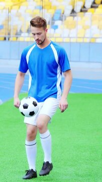 vertical video of football player standing on grass and bouncing ball