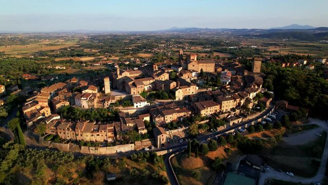 Lucignano Tuscany Aerial Reveal Video. Sunset over Medieval Elliptical Walled Town. Focus on Church and Ring Streets Transition to Tuscan Fields Panorama