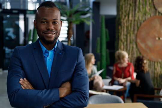 Confident businessman with arms crossed standing in office