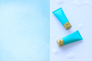 Blue cosmetic bottles shower gel on plastic borad with foam bubbles background in the bathroom
