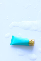 Blue cosmetic bottle shower gel on plastic board with foam bubbles background in the bathroom