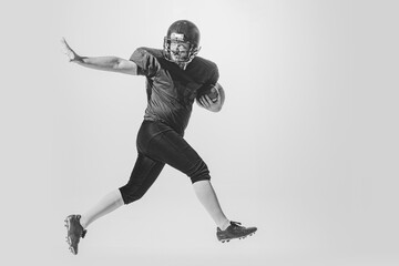 Dynamic portrait of american football player in action and motion isolated on white background. Concept of sport, achievements, retro style. Monochrome