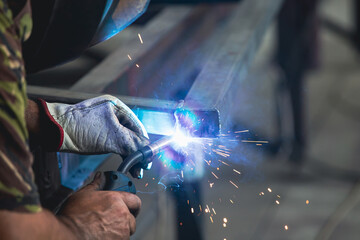 Industry worker welding iron pieces at work