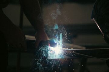 Industry worker welding iron pieces at work