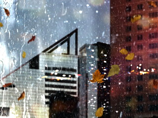 Autumn Rain  in city people with umbrellas,and yellow leaves on window rain drops weather forecast background 