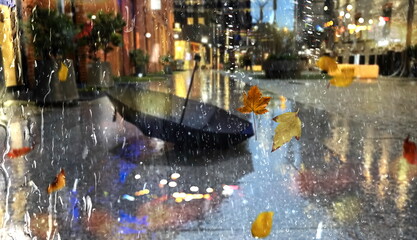 Fototapeta na wymiar Autumn Rain in city people with umbrellas,and yellow leaves on window rain drops weather forecast background 