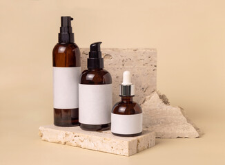 Brown glass cosmetic bottles on beige stone on light beige close up. label Mockup
