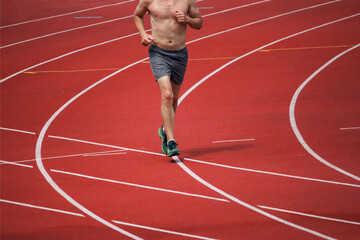 Obraz premium Rear view of an male athlete starting his sprint on an stadium running track