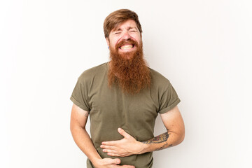 Young caucasian red-haired man isolated on white background touches tummy, smiles gently, eating and satisfaction concept.