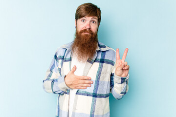 Young caucasian red-haired man isolated on blue background taking an oath, putting hand on chest.