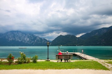 Attersee - famous Austrian turquoise lake. The view on two old ladies sitting on the wooden bench...