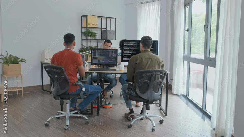 Wall mural slowmo of team of indian programmers sitting by their computers at office desk, writing program code