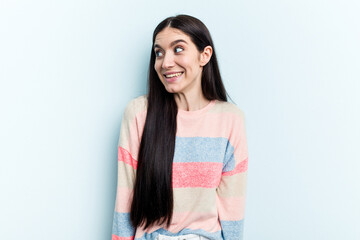 Young caucasian woman isolated on blue background laughs and closes eyes, feels relaxed and happy.