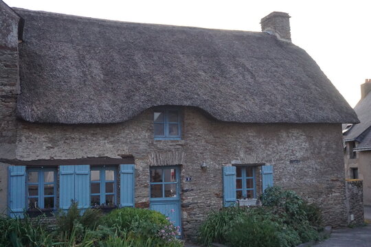 thatched cottage house in brittany france with blue shutters