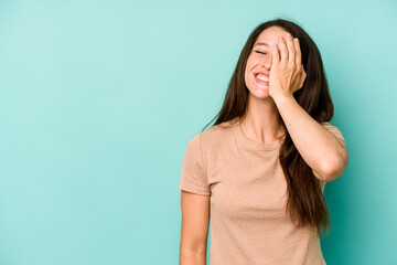 Young caucasian woman isolated on blue background laughing happy, carefree, natural emotion.
