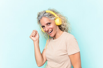 Middle age caucasian woman listening to music isolated on blue background